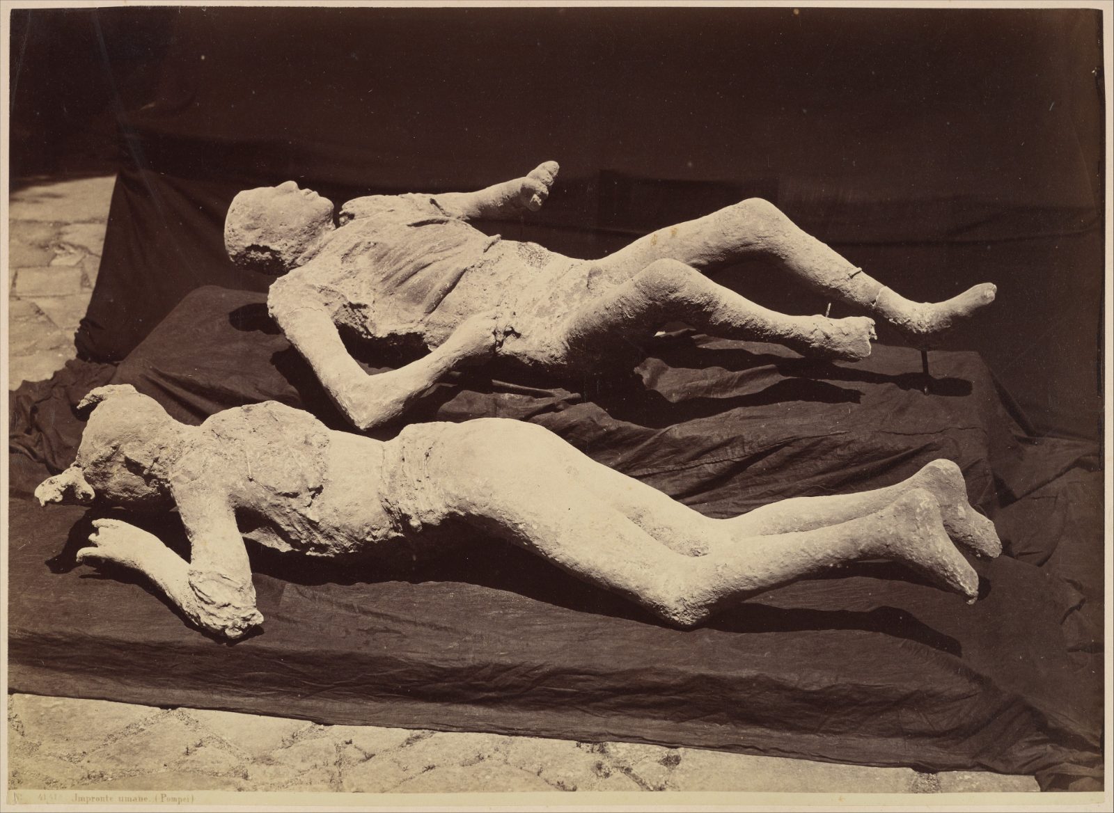 A nineteenth-century photograph of several plaster casts of Vesuvius victims, adults lying as they fell, on display in Pompeii